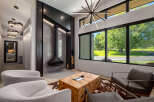 Experience modern luxury in this stunning living room, featuring a unique suspended fireplace and a striking starburst chandelier.