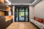 Experience seamless indoor-outdoor living with this stunning room featuring a modern built-in dark wood shelving unit with integrated lighting.