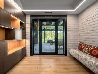 Experience seamless indoor-outdoor living with this stunning room featuring a modern built-in dark wood shelving unit with integrated lighting.