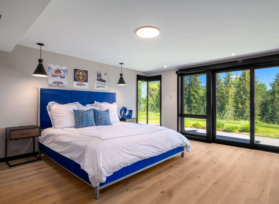 Experience ultimate comfort in this modern bedroom featuring a plush blue upholstered bed and crisp white linens.
