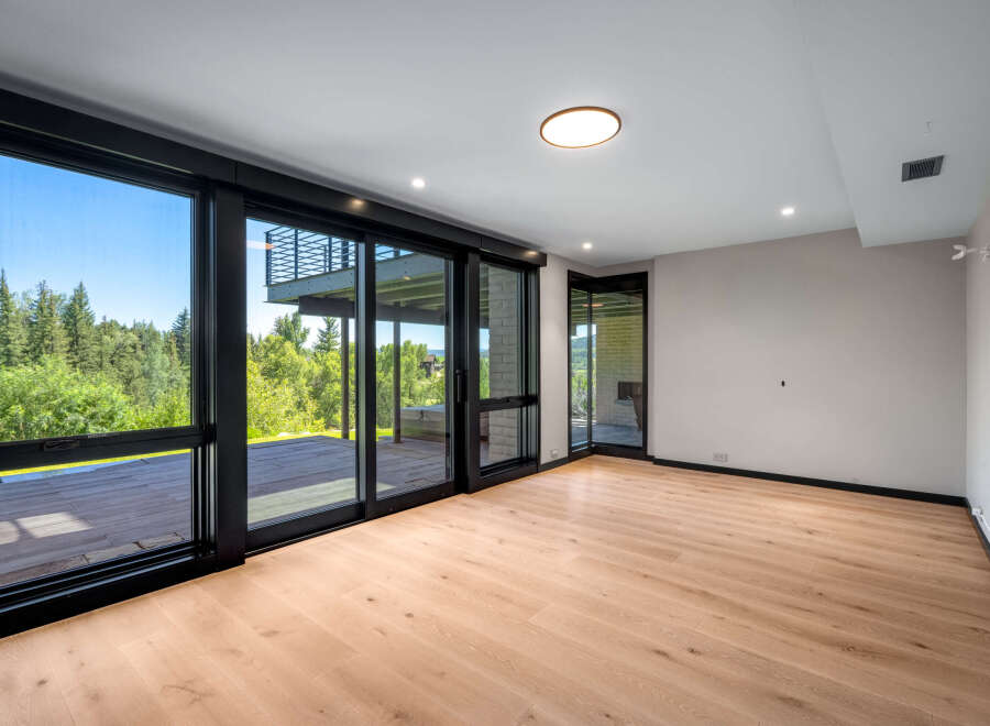 Experience seamless indoor-outdoor living with expansive floor-to-ceiling windows and sliding glass doors that open onto a private deck.