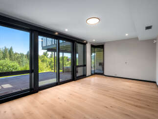 Experience seamless indoor-outdoor living with expansive floor-to-ceiling windows and sliding glass doors that open onto a private deck.