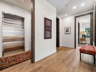 Experience luxury living with this stunning hallway featuring a sleek stainless steel elevator and elegant hardwood floors.