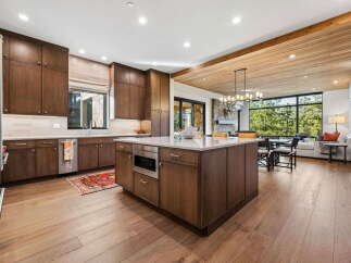 Experience luxury living in this stunning modern kitchen, featuring rich dark wood cabinetry and a spacious island with a built-in microwave.