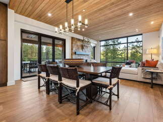 Experience luxurious mountain living in this stunning dining room, featuring a grand wooden table with seating for eight and a striking stone fireplace as a focal point.