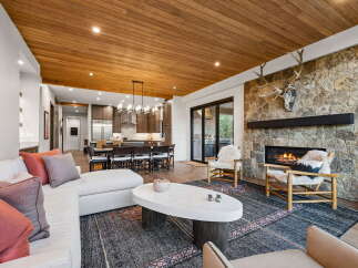 Experience luxurious mountain living in this stunning open-concept great room, featuring a soaring wood-paneled ceiling and a magnificent stone fireplace.