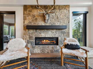 Experience rustic luxury with this stunning living room featuring a floor-to-ceiling stone fireplace, perfect for cozy evenings.
