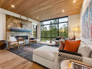 Experience luxurious mountain living in this stunning great room, featuring a dramatic stone fireplace and a vaulted wood-paneled ceiling.