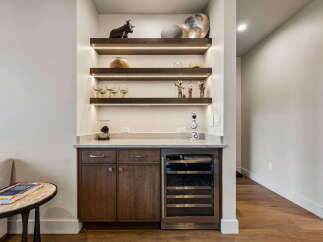 This modern wet bar features dark wood cabinetry, a sleek marble countertop, and a built-in wine cooler, perfect for entertaining.