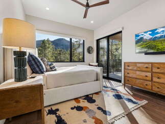 Experience breathtaking mountain views from this stunning bedroom, featuring a large picture window that frames the lush forest scenery.