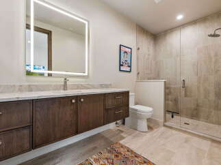 Experience modern luxury in this stunning bathroom, featuring a sleek vanity with ample storage and a large, illuminated mirror.