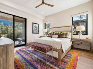 Experience luxurious mountain living in this stunning bedroom featuring a king-sized bed adorned with plush pillows and a vibrant, patterned bench.