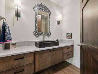 This modern bathroom features a striking black vessel sink atop a sleek white marble countertop.