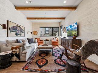Experience rustic luxury in this inviting living room, featuring a plush sofa adorned with decorative pillows and a cozy throw.