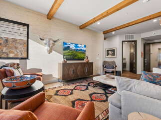 Experience rustic elegance in this inviting living room, featuring exposed wooden beams and a textured accent wall.
