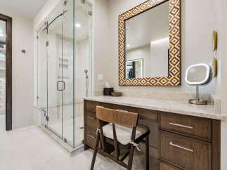 Experience luxury in this master bathroom featuring a spacious glass-enclosed shower and a dedicated vanity area with a decorative mirror.