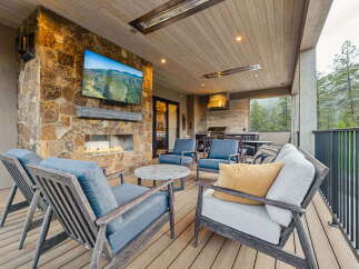 Experience luxurious outdoor living with this stunning covered patio, featuring a cozy fireplace and a mounted television for entertainment.