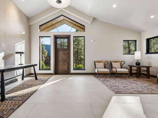 Step into a grand entryway featuring a soaring vaulted ceiling and a striking triangular window that frames breathtaking mountain and forest views.