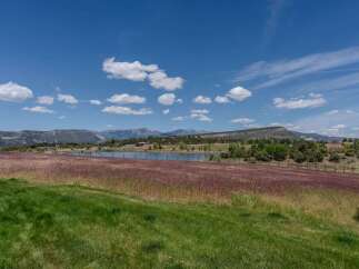 Discover this stunning property featuring a serene lake, vast fields of native grasses, and breathtaking mountain views.