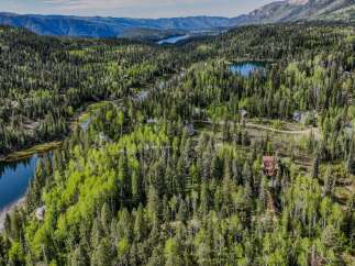 Discover a serene mountain retreat nestled amidst a lush forest and sparkling blue waters.