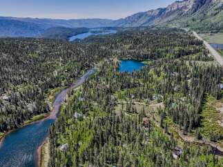 Discover your dream mountain retreat nestled amidst a lush forest with a serene river winding through the landscape.