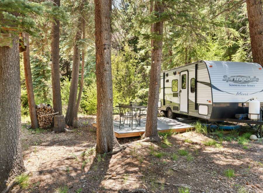 Experience the perfect blend of nature and comfort with this charming campsite featuring a Springdale Summerland Series Mini travel trailer.