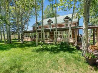 Nestled amongst mature aspen trees, this charming log home offers a serene retreat with its rustic architecture and picturesque setting.