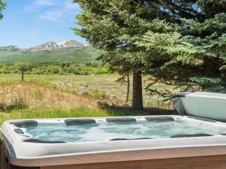 Relax and unwind in this luxurious hot tub, offering breathtaking views of snow-capped mountains and lush green valleys.