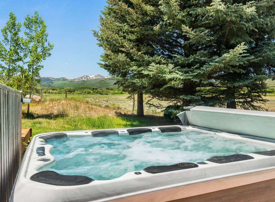 Relax and unwind in this luxurious hot tub, offering stunning views of the surrounding mountains and lush greenery.