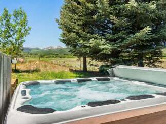 Relax and unwind in this luxurious hot tub, offering stunning views of the surrounding mountains and lush greenery.