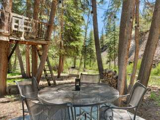 Enjoy the great outdoors with this charming backyard oasis, featuring a rustic treehouse and a cozy swing set perfect for relaxation and play.