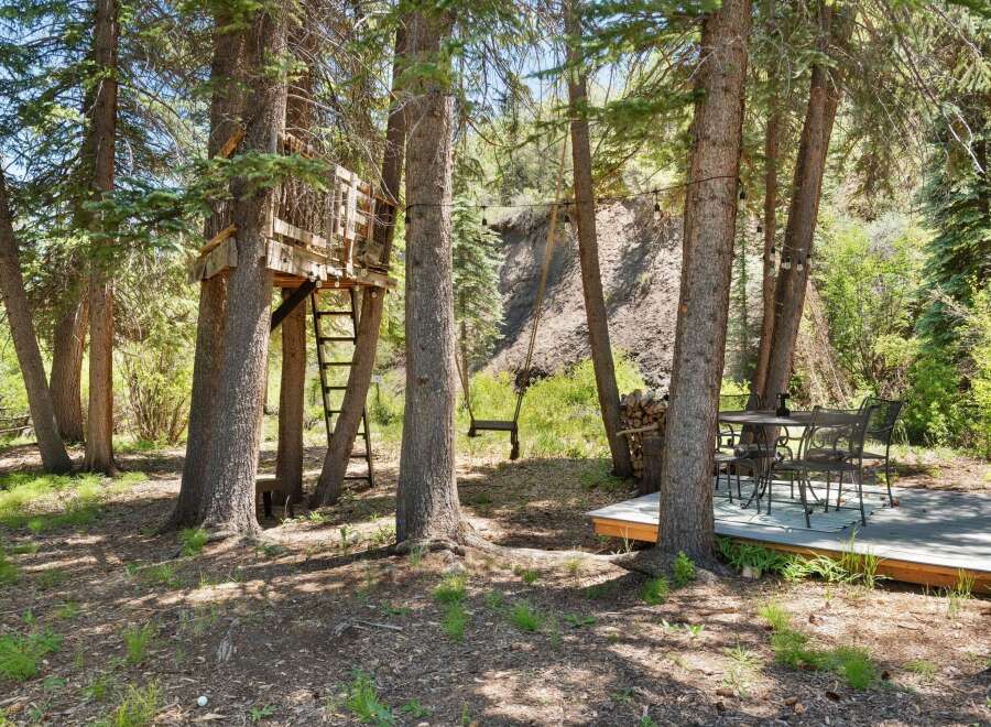 Escape to this enchanting forest retreat featuring a charming treehouse with a ladder for access.