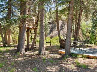 Escape to this enchanting forest retreat featuring a charming treehouse with a ladder for access.