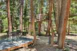 Enjoy the outdoors with this charming backyard setup, featuring a rustic treehouse and a dining area perfect for al fresco meals.