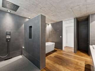 Experience modern luxury in this stunning bathroom featuring a spacious walk-in shower with a rainfall showerhead and sleek grey tilework.