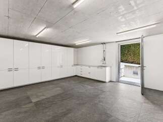 Discover this modern garage space featuring sleek white cabinetry for ample storage and a convenient utility sink.