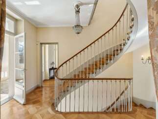 Step into elegance with this stunning curved staircase, featuring a rich wooden handrail and intricate balusters.