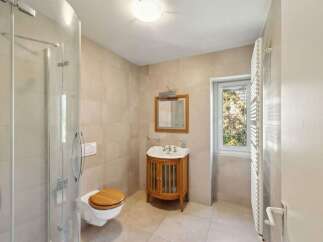 Discover this charming bathroom featuring a modern shower enclosure and a classic wooden vanity with a ceramic sink.