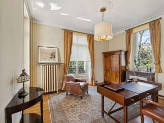 Step into this elegant home office, featuring a classic leather armchair and a distinguished wooden desk.