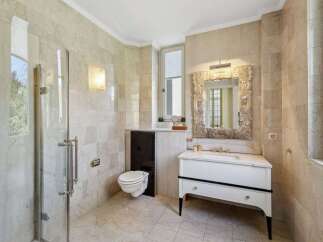 Experience luxury in this elegant bathroom, featuring a spacious glass-enclosed shower and a sophisticated vanity with a decorative mirror.