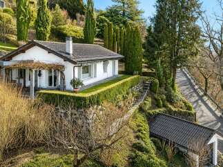Nestled on a lush hillside, this charming white house offers a serene retreat with stunning natural surroundings.
