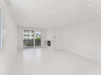 Experience modern living in this bright and airy living room, featuring a sleek white fireplace and expansive glass doors leading to a balcony.