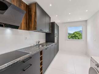 Discover this modern kitchen featuring sleek dark cabinetry, a granite countertop, and a built-in induction hob.