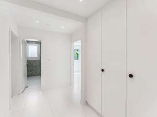 Step into this bright and airy hallway, featuring pristine white walls and floors that create a sense of spaciousness.