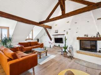 Experience rustic charm in this spacious living room, featuring exposed wooden beams and a striking white stucco fireplace.