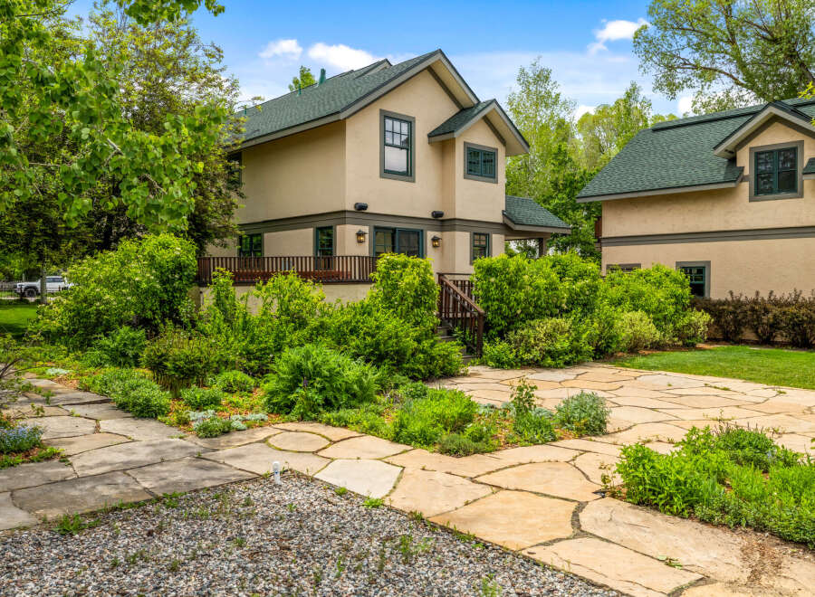 Discover this charming home featuring a light-colored stucco exterior and a durable green roof.