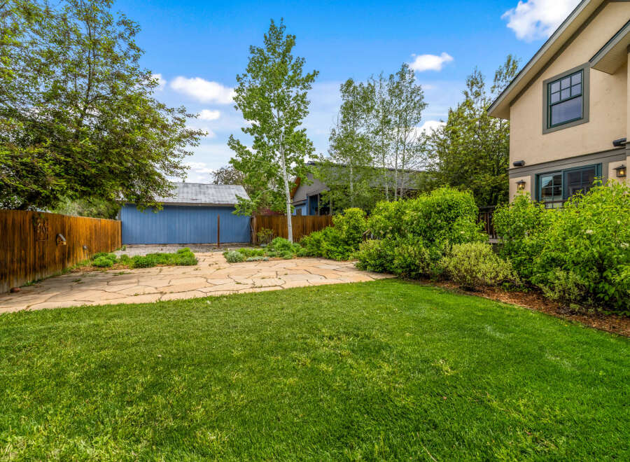 Enjoy the outdoors in this spacious backyard featuring a large flagstone patio perfect for entertaining and a lush green lawn.