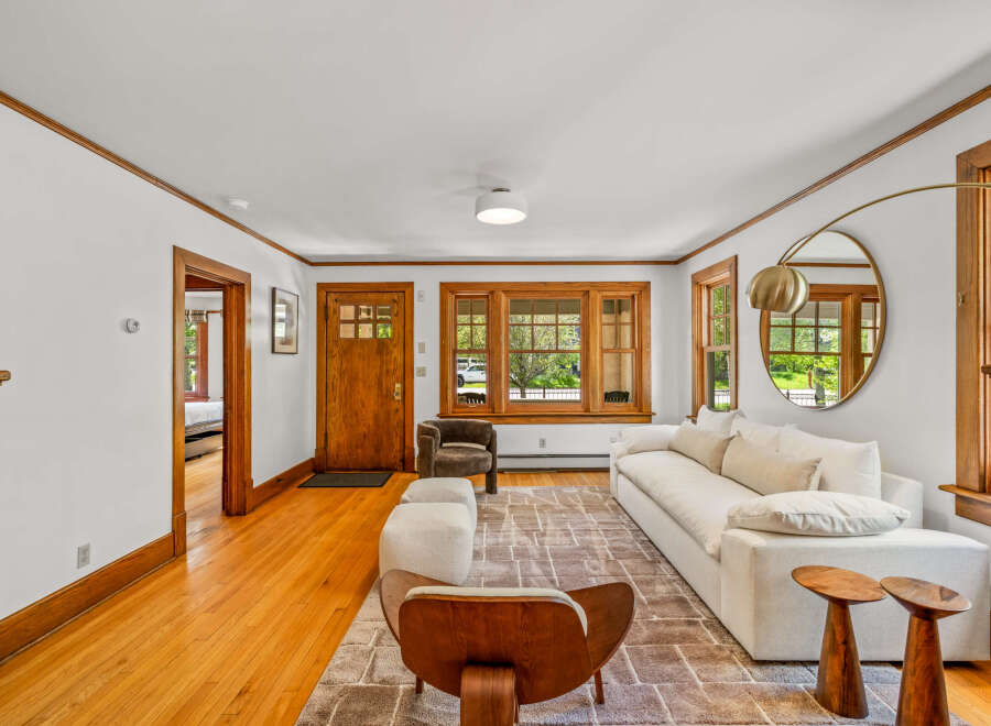 Step into this inviting living room featuring a plush white sectional sofa complemented by a textured rug and unique wooden side tables.