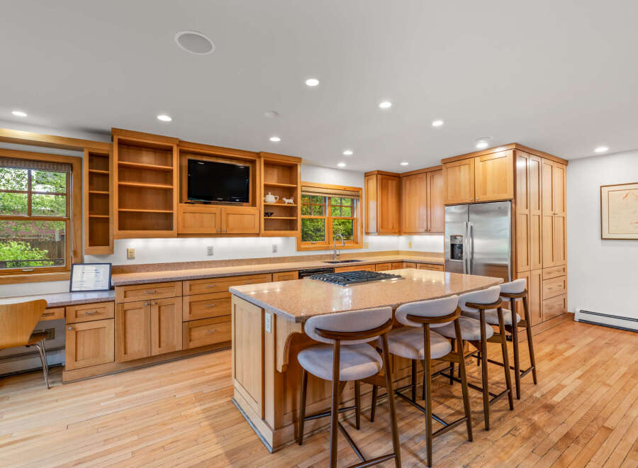 This spacious kitchen boasts custom light wood cabinetry, granite countertops, and a large island perfect for entertaining.
