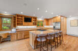 This spacious kitchen boasts custom light wood cabinetry, granite countertops, and a large island perfect for entertaining.